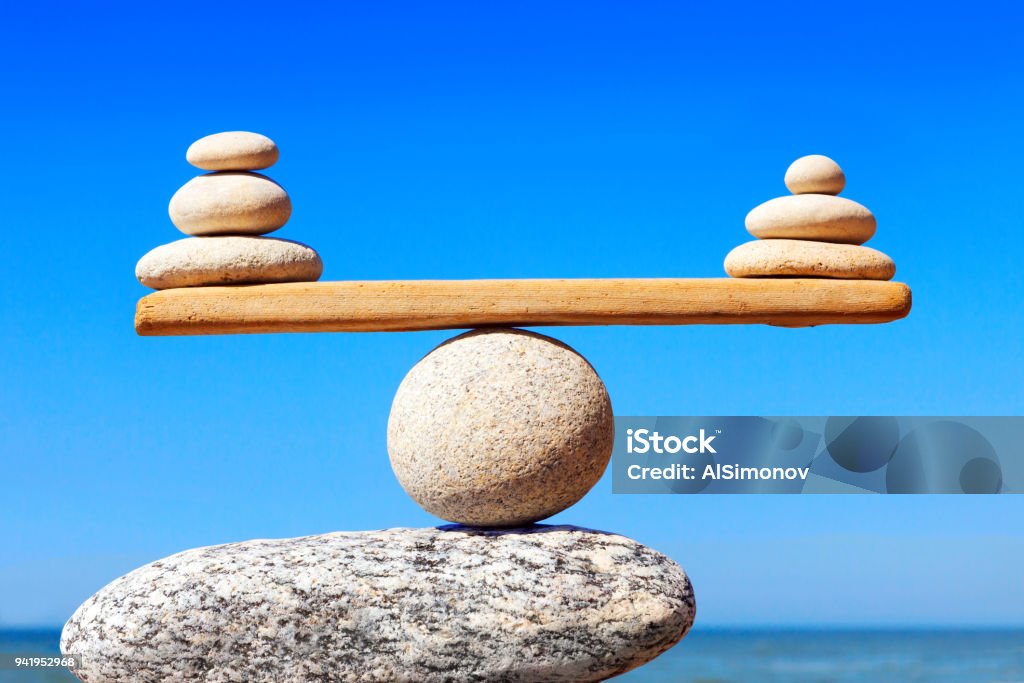 Concept of harmony and balance. Balance stones against the sea. Symbolic scales of stones on the background of the sea and blue sky. Concept of harmony and balance. Pros and cons concept Wellbeing Stock Photo