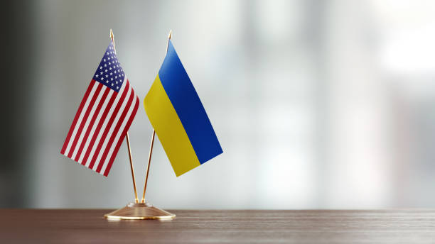 American And Ukrainian Flag Pair On A Desk Over Defocused Background American and Ukrainian flag pair on desk over defocused background. Horizontal composition with copy space and selective focus. ukraine flag stock pictures, royalty-free photos & images