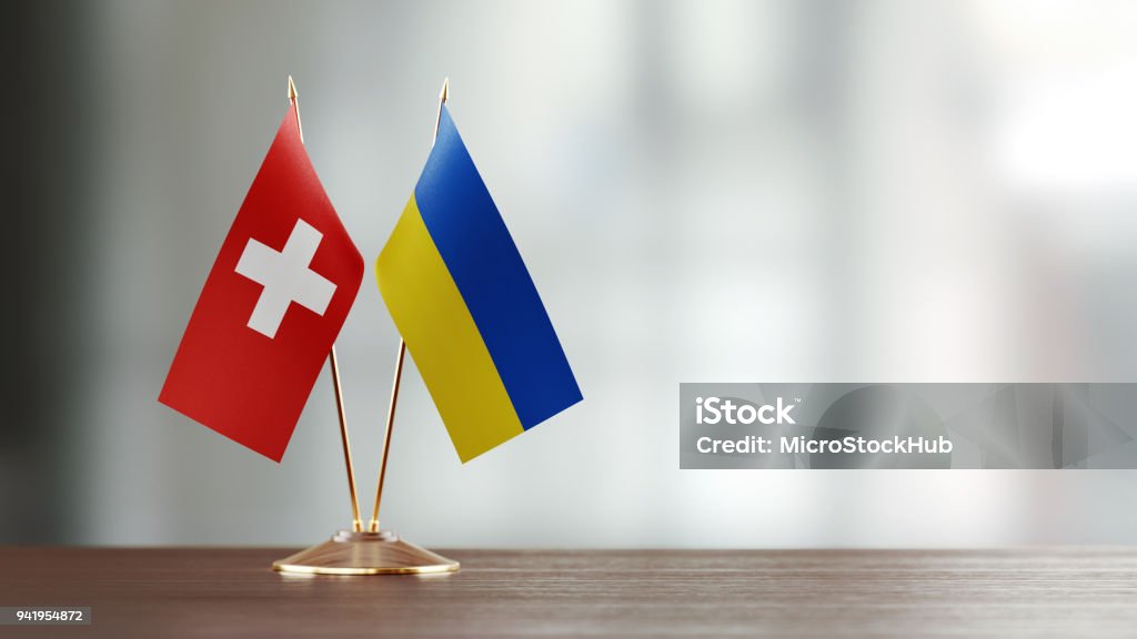 多重の背景の上の机の上のスイスとウクライナの国旗ペア - ウクライナのロイヤリティフリーストックフォト