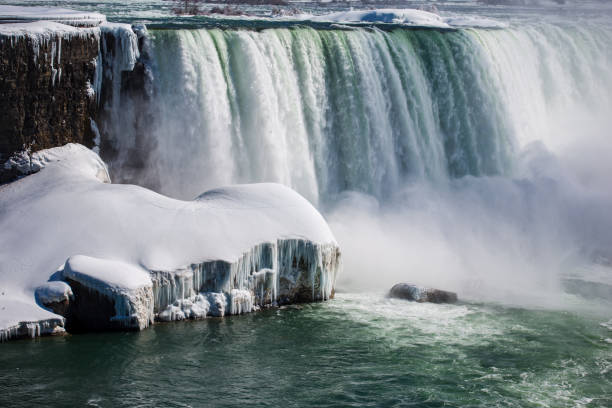 istock Frozen Niagara Falls in spring with snowy river banks and chilling mist 941955058