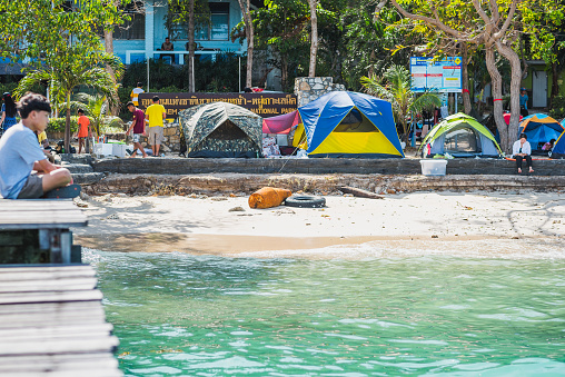 Ko Samet, Thailand - December 31, 2017: Several tents and tourists (unidentified) on Ao Pacha beach on Koh Samet island along the teal seawaters.
