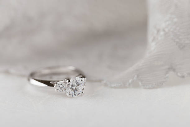 istock White gold wedding ring with diamonds on white background with lace 941965632