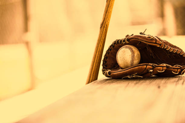 saison de baseball est ici.  bat, gant et boule sur le banc de l’étang-réservoir. - dugout baseball bench bat photos et images de collection