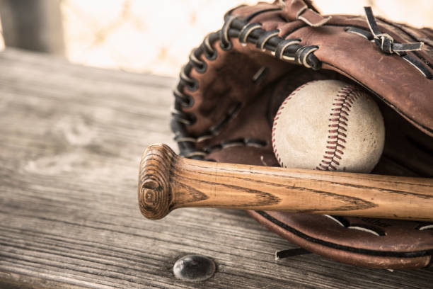 saison de baseball est ici.  bat, gant et boule sur le banc de l’étang-réservoir. - dugout baseball bench bat photos et images de collection