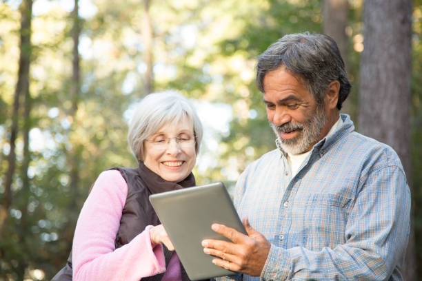 istock Active senior adult couple using digital tablet outdoors. 941972300