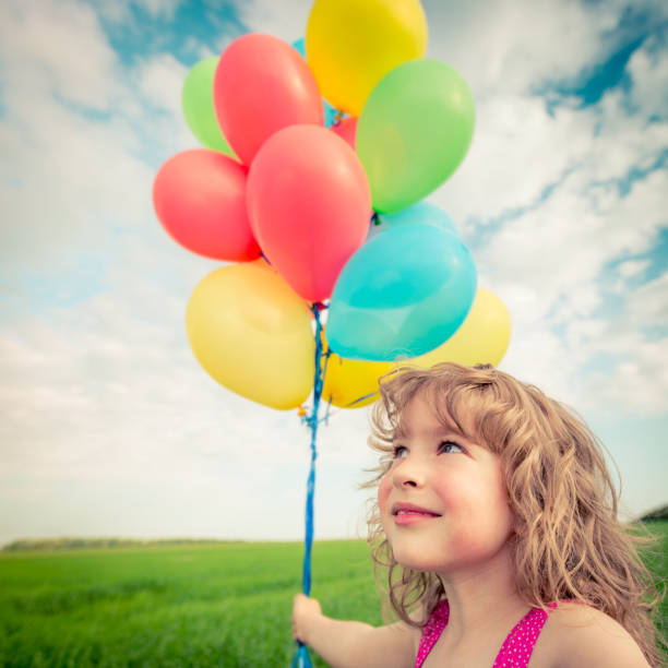 istock Child with toy balloons in spring field 941972912
