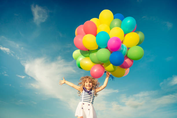 istock Child with toy balloons in spring field 941972928