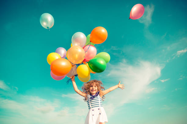 istock Child jumping with toy balloons in spring field 941973110