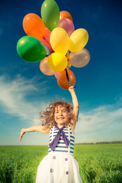 istock Child with toy balloons in spring field 941975360