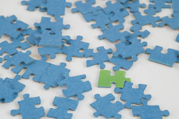 istock One green jigsaw puzzle piece between blue pieces, white background 941975464