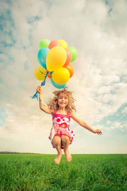 istock Child with toy balloons in spring field 941975574