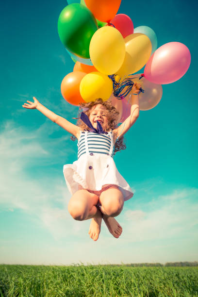 istock Child with toy balloons in spring field 941975652