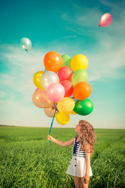 istock Child with toy balloons in spring field 941975672