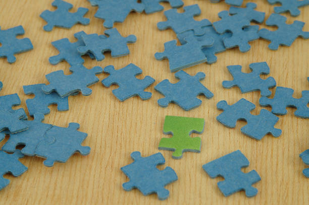 istock One green jigsaw puzzle piece between blue pieces, wooden background 941976342