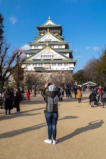 Osaka, Japan - 29th January, 2018.\nA winter, day shot of tourists taking pictures of Osaka Castle in Osaka, Japan.\nThis area attracts thousands of locals and tourists every year and offers some amazing walks and scenery.