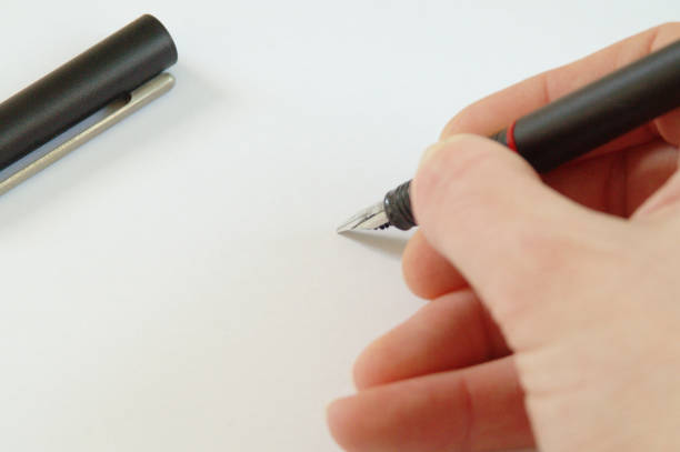 istock hand writing with Modern caligraphic fountain pen on white paper 941984930