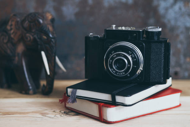 istock Two notebooks and old camera on the table, tinted and filtered 941988636