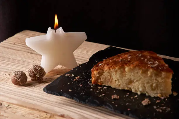 Photo of Home baked apple pie on shale board and wooden table near Candle in the form of stars