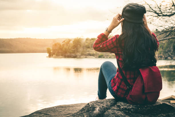 istock Woman Sitting On Rock Sitting Against Sky 942003324