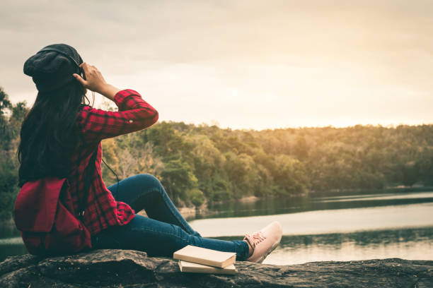 istock Woman Sitting On Rock Sitting Against Sky 942003714