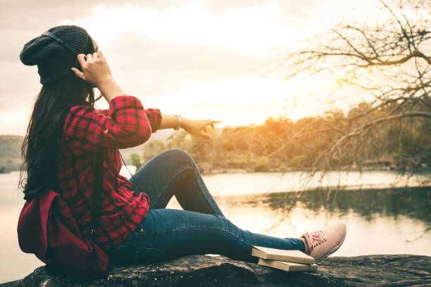 istock Woman Sitting On Rock Sitting Against Sky 942004762