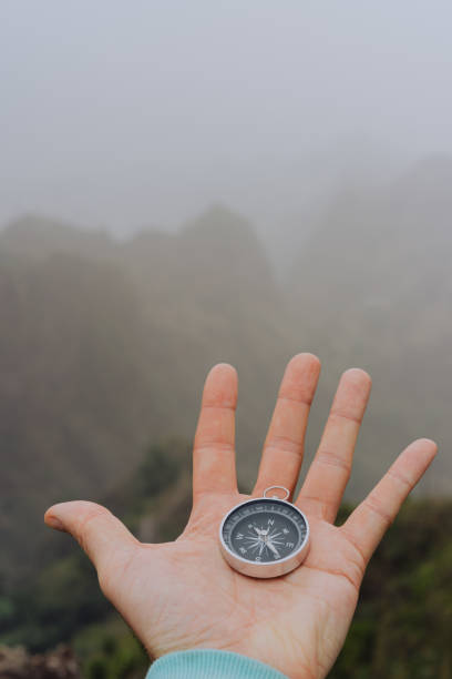 istock Man palm holding compass. Foggy mountainous landscape 942019596