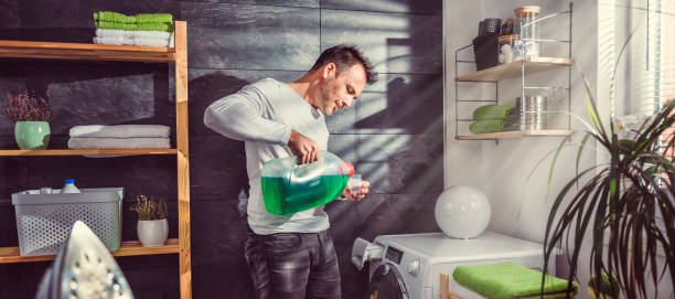 istock Man pouring liquid laundry detergent In the bottle cap 942029786