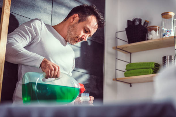 istock Man pouring liquid laundry detergent In the bottle cap 942030128
