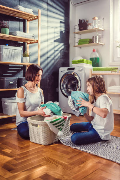istock Mother and daughter talking and sorting laundry on the floor 942113088
