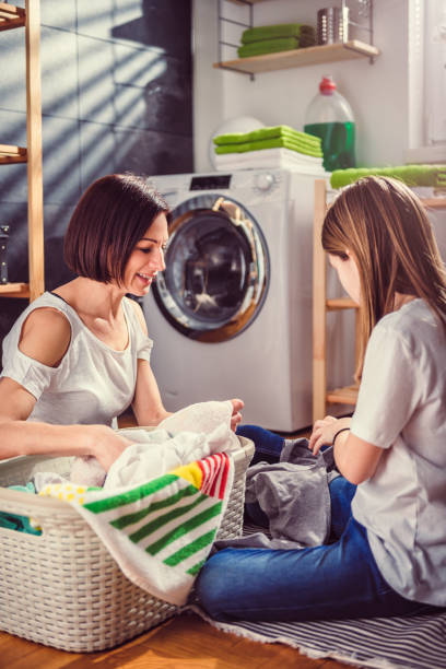 istock Mother and daughter talking and sorting laundry on the floor 942114568