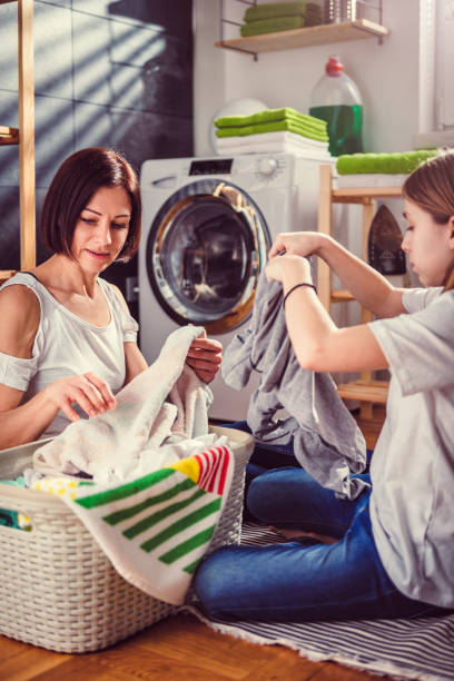 istock Mother and daughter talking and sorting laundry on the floor 942114882