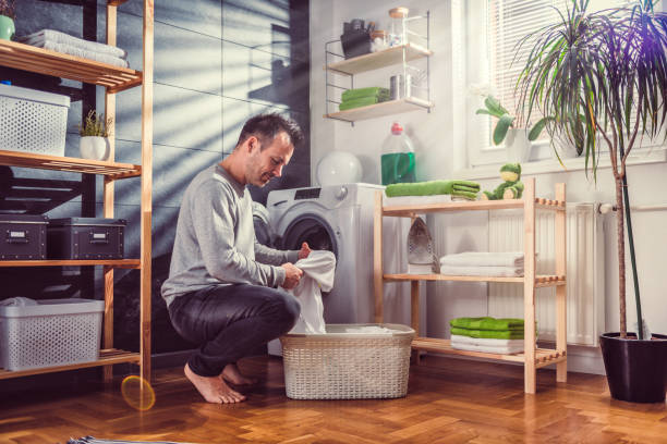istock Man putting clothes into washing machine 942115174