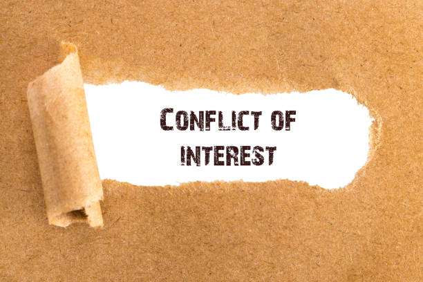 istock text Conflict of interest appearing behind torn brown paper 942117654