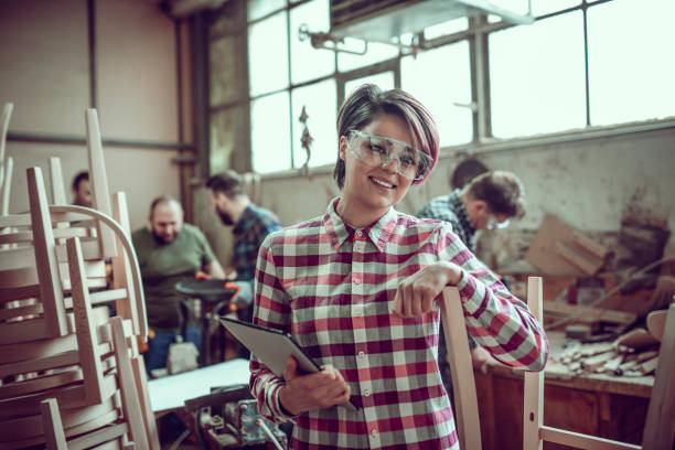 istock Young Smiling Carpenter in Front of Working Team in her Work Shop 942118526
