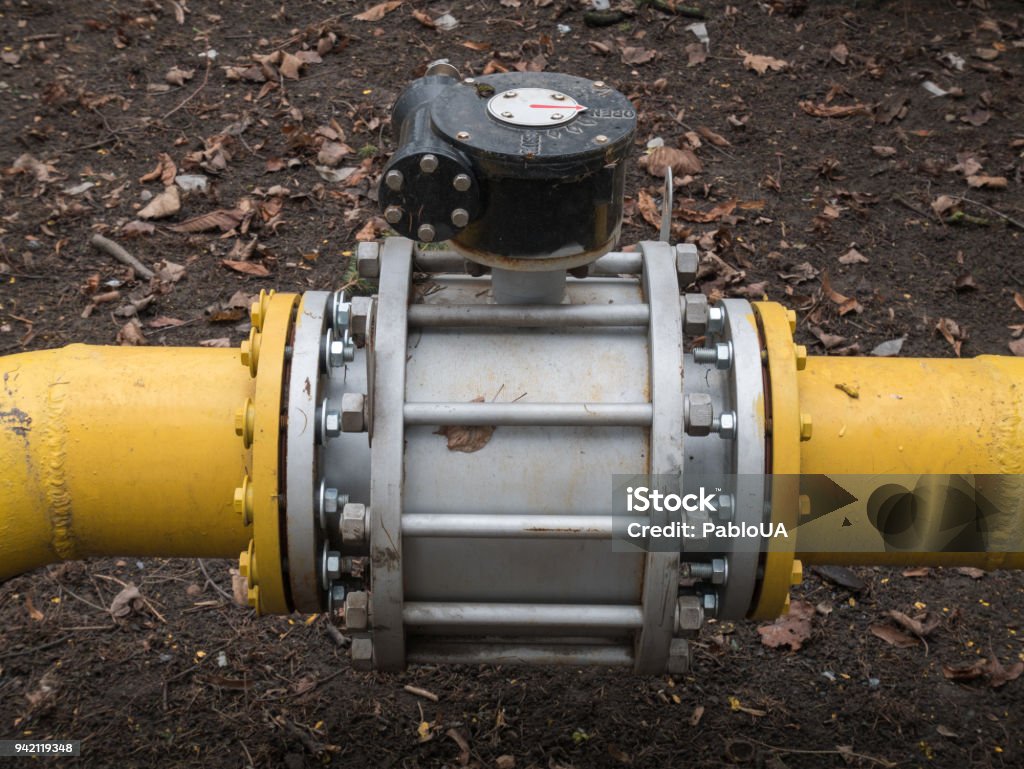 close up shot big valve on a thick yellow gas oil water pipeline tube big massive valve on a thick yellow gas water oil steel metal pipelines tubes Engineering Stock Photo