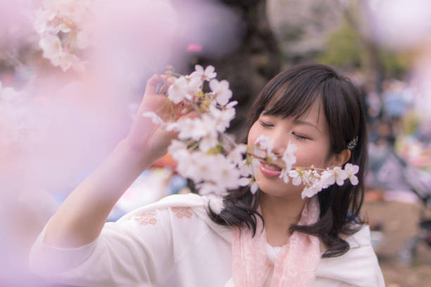 istock Young woman being relaxed with cherry blossoms 942119442