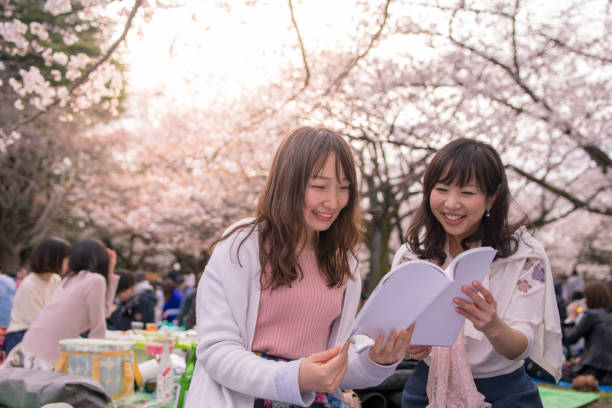 Young women reading book in hanami party