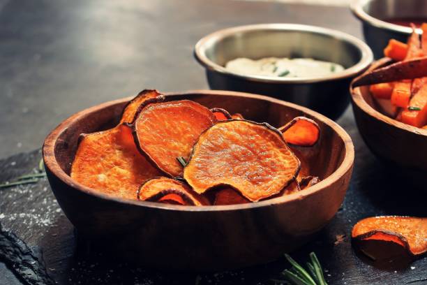 istock Homemade baked sweet potato chips with dips on dark moody background, selective focus 942121746