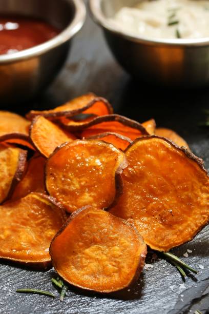 istock Homemade baked sweet potato chips with dips on dark moody background, selective focus 942121774