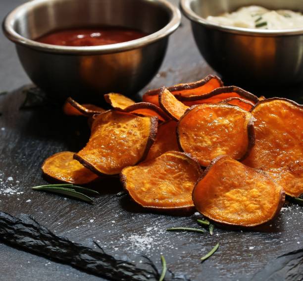 istock Homemade baked sweet potato chips with dips on dark moody background, selective focus 942121828