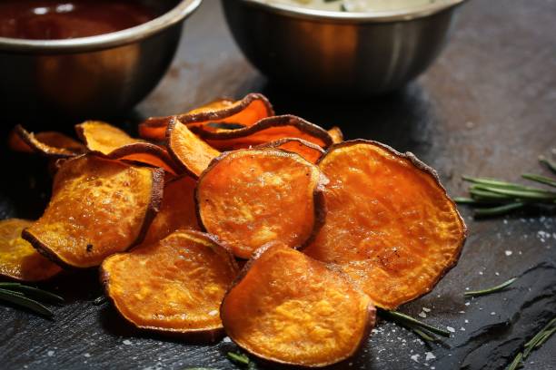 istock Homemade baked sweet potato chips with dips on dark moody background, selective focus 942121946