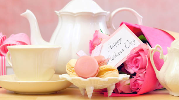 Mother's Day tea setting with macaron cookies, pink roses and gift, closeup Happy Mother's Day tea setting with teapot, macaron cookies, pink roses and gift close up. mothers day tea stock pictures, royalty-free photos & images