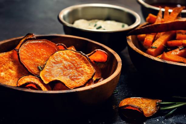 istock Homemade deep fried sweet potato chips on dark moody background, selective focus 942122414