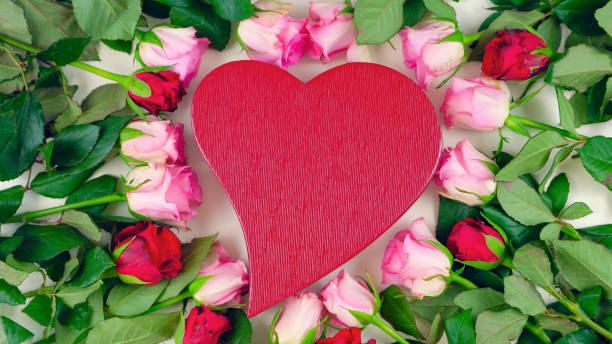 istock Red heart gift box surrounded by pink and red roses overhead 942122496