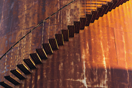 A curving staircase wraps around an abandoned oil storage tank.