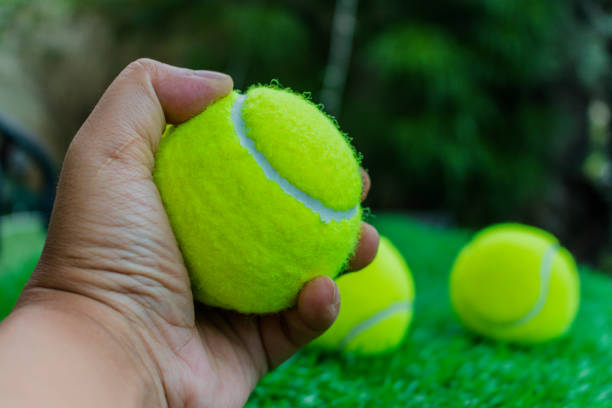 istock Tennis ball in man hand with artificial grass background 942139066