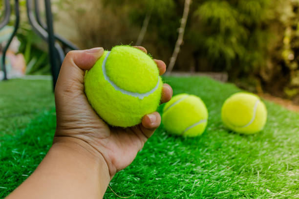 istock Tennis ball in man hand with artificial grass background 942139126