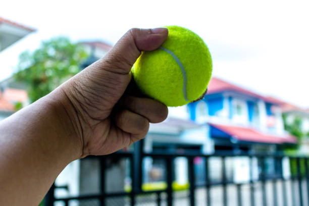 istock Tennis ball in man hand with artificial grass background 942140266