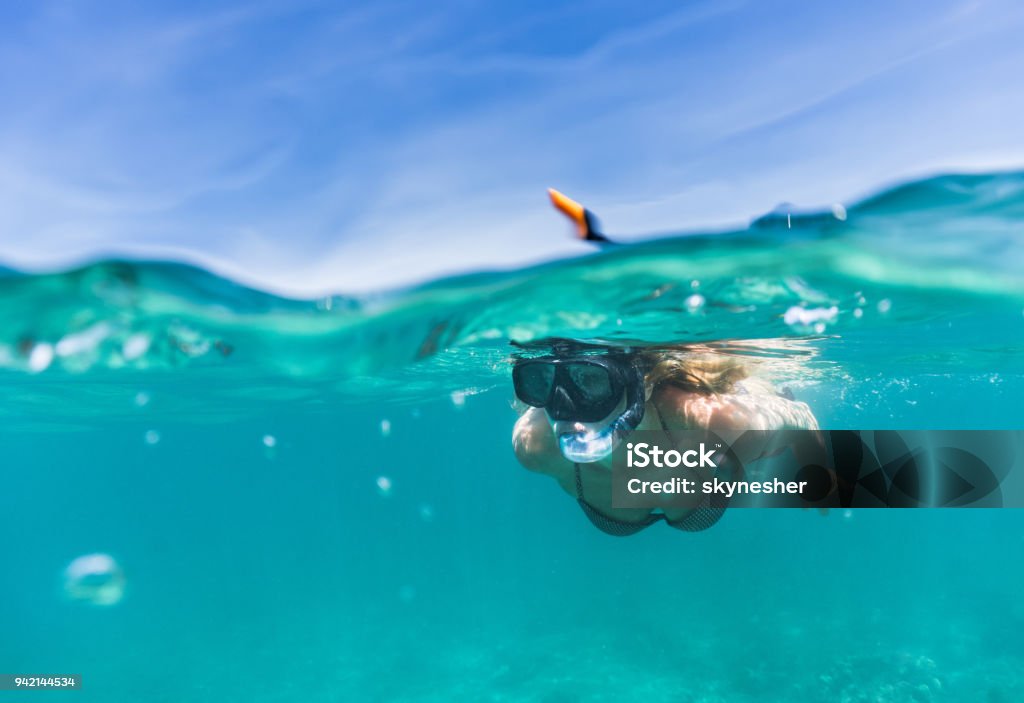 Woman exploring the sea while snorkeling in summer day. Woman snorkeling during her summer vacation under the sea. Snorkeling Stock Photo