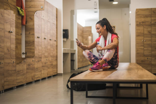 istock Happy female athlete using cell phone at gym's dressing room. 942146036